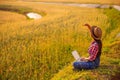 Female farmer using laptop computer in gold wheat crop field