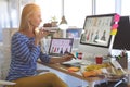 Female fashion designer talking on mobile phone while working at desk Royalty Free Stock Photo