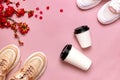 Female Fashionable Sneakers, Coffee or tea paper cup and spring branches of red flowers on pink background top view flat lay. Take Royalty Free Stock Photo