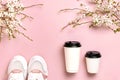 Female Fashionable Sneakers, Coffee or tea paper cup and spring branches of white flowers on pink background top view flat lay. Royalty Free Stock Photo