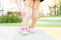 Female fatty runner athlete leg injury and pain. Hands grab painful leg while running in the park