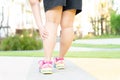 Female fatty runner athlete leg injury and pain. Hands grab painful leg while running in the park