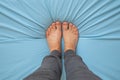 Female feet barefoot on a light blue mattress, top to bottom view