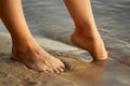 Female feet barefoot on a sandy beach in the water. Close-up of beautiful female legs. Wet foot Royalty Free Stock Photo