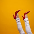 Female feet in beautiful red stiletto shoes, yellow background copy space. Royalty Free Stock Photo