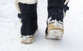 Female feet in black boots walking in winter snow