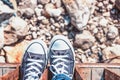 Female feet in blue sneakers on a stony beach Royalty Free Stock Photo