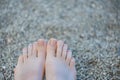 Female feet with clear pedicure. Woman legs with clear nail design on small rocks background Royalty Free Stock Photo