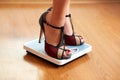 Female feet in color stilettos with weight scale