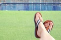 Female feet in flat leather sandals on the background of the pool and green lawn Royalty Free Stock Photo