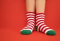 Female feet in fluffy New Year or Christmas warm socks. The colors of the socks are red and white stripes and green heels and tips Royalty Free Stock Photo