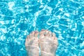 Female feet with glitter pedicure under clear pool water