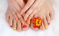 Female feet and hands with colorful manicure with red-orange flowers. Soft focus image Royalty Free Stock Photo