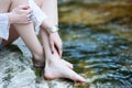 Female feet and hands in ornaments on the stony bank of a mountain river