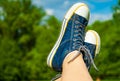 Female feet in jeans sneakers on the background of a sky and tree Royalty Free Stock Photo