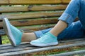 Female feet in jeans and sports shoes on a bench close-up Royalty Free Stock Photo