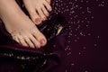 Female feet with pink pedicure. Woman legs with glitter pink nail design on pink fabric with golden paillettes