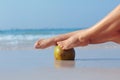 Female feet propped on coconut on sea background Royalty Free Stock Photo