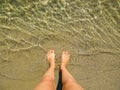 Female feet with red, coral pedicure steps into clear seawater. Royalty Free Stock Photo