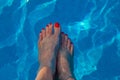 Female feet with red varnished toenails inside pool water Royalty Free Stock Photo