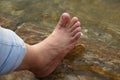 Female feet in running water. Close-up of female legs wearing jeans and resting while wetting her feet. BCN Royalty Free Stock Photo