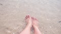 Female feet on the sand, the sea wave covers the female legs. 4k, slow motion