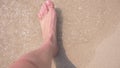 Female feet on the sand, the sea wave covers the female legs. 4k, slow motion