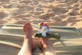 Female feet on the sand sith a Hawaiian, flower band