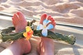 Female feet on the sand sith a Hawaiian, flower band