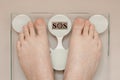 female feet on the scales, the word SOS on the display, weighing on the scales, the concept of overweight, abdominal obesity Royalty Free Stock Photo