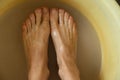 Female feet in soapy water, washing in a plastic bowl