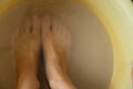 Female feet in soapy water, washing in a plastic bowl