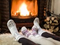 Female feet in soft wool socks and burning fire in fireplace at the background. Warming and unwinding near fireplace with a cup of Royalty Free Stock Photo