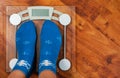 Female feet standing on electronic scales for weight control in Christmas socks on wooden floor background. with copy space.