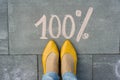 Female feet with text 100 percent written on grey sidewalk