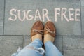 Female feet with text sugar free written on grey sidewalk