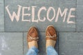 Female feet with text welcome written on grey sidewalk Royalty Free Stock Photo