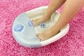 Female feet in a vibrating foot massager. Electric massage foot bath. Relax after work