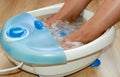 Female feet in a vibrating foot massager. Electric massage foot bath. Relax after work