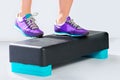 Female feet in violet sneakers on fitness aerobic step. Royalty Free Stock Photo