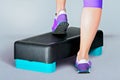 Female feet in violet sneakers on fitness step. Royalty Free Stock Photo