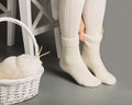 Female feet in white knitted stockings and socks near the basket