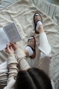 Female feet in white socks and slippers on the bed. Girl reads book sitting on sofa top view. Slippers close-up Royalty Free Stock Photo