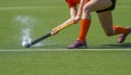 Female field hockey player passing to a team mate on a modern, water artificial astroturf field