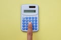 Female Finger press button Modern blue digital calculator is on a yellow background. Royalty Free Stock Photo