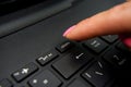 Female finger presses delete button on black laptop Royalty Free Stock Photo