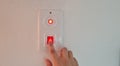 Woman switching off red button light on white wall