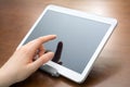 Female Finger Touches A Blank White Business Tablet In A Holder On A Desk