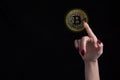 Female finger touching bitcoin over isolated black background