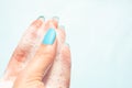 Female fingers in white soapy foam on a blue background Royalty Free Stock Photo